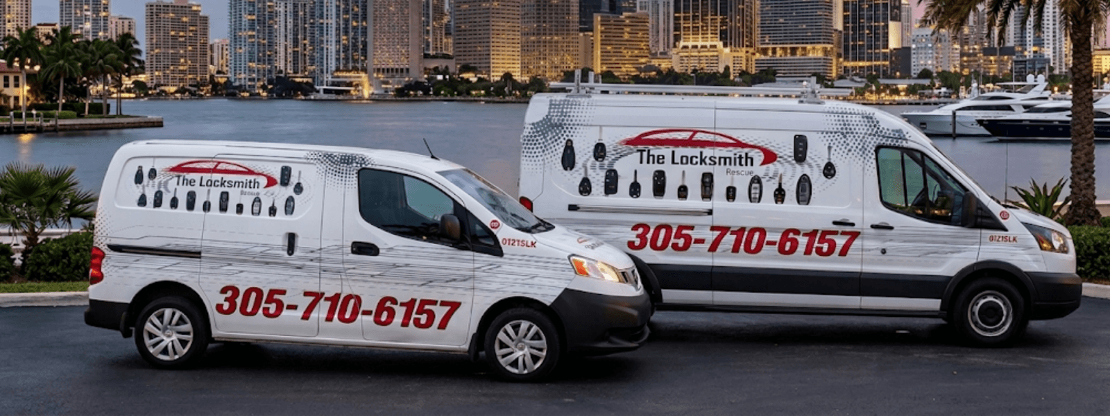 Two Locksmith Rescue vans parked in front of the downtown Miami skyline at dusk