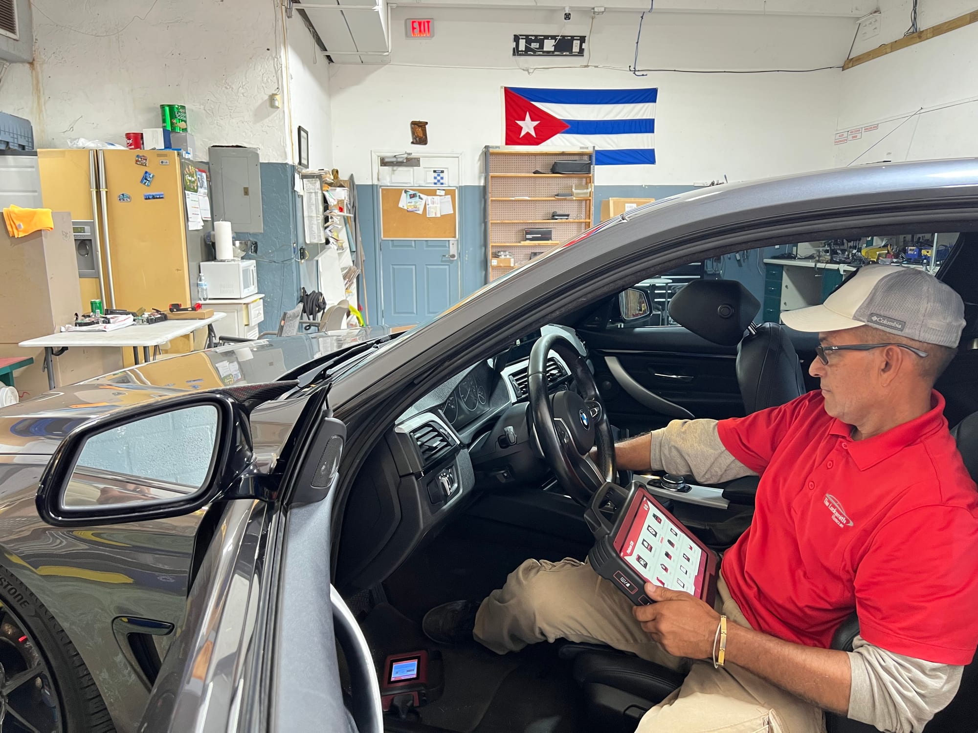 Eddy sitting in the driver's seat of a BMW in his shop, holding a diagnostic tablet on his lap
