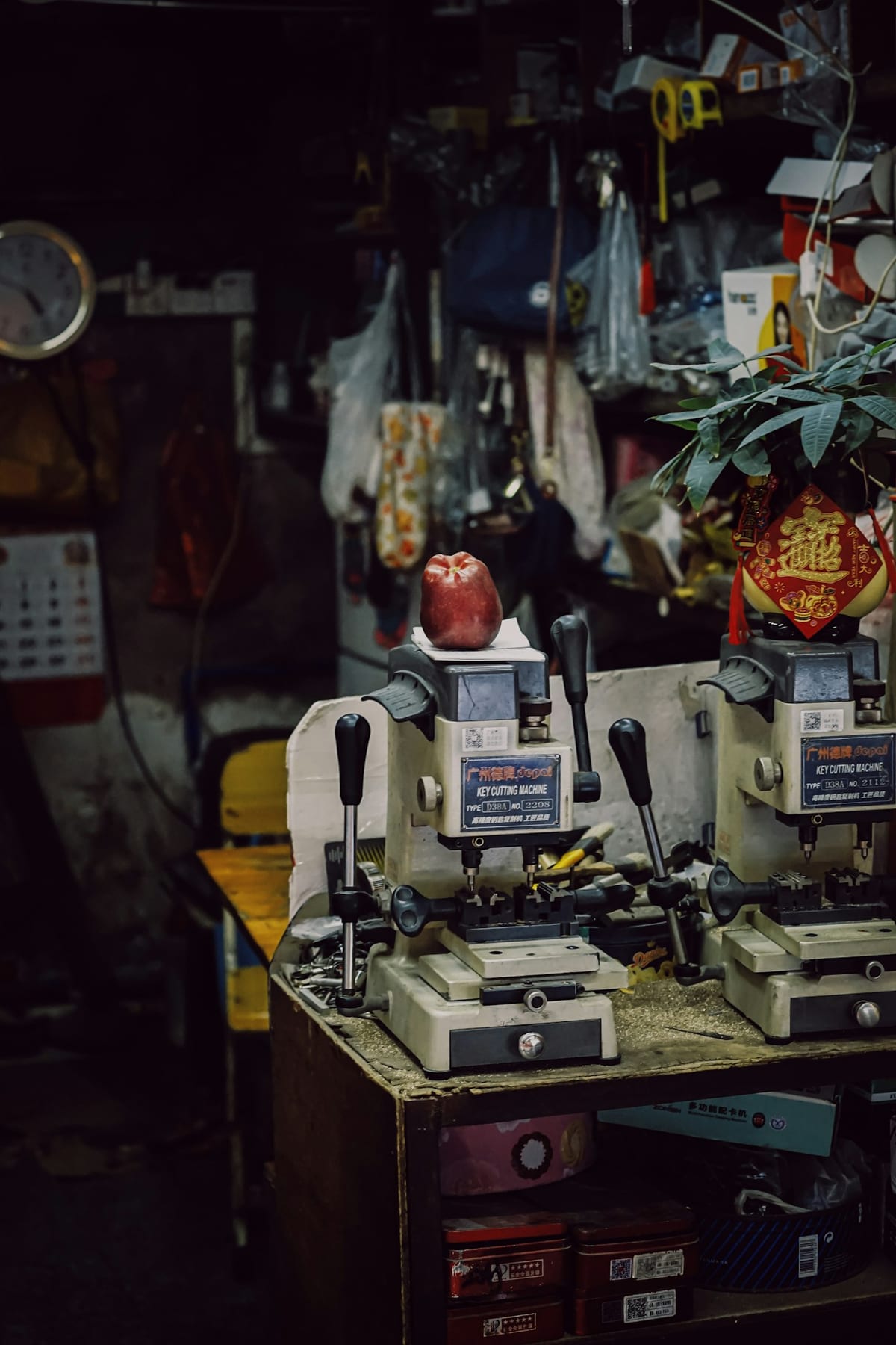 Two key cutting machines set up on a workbench in a cluttered locksmith's workshop